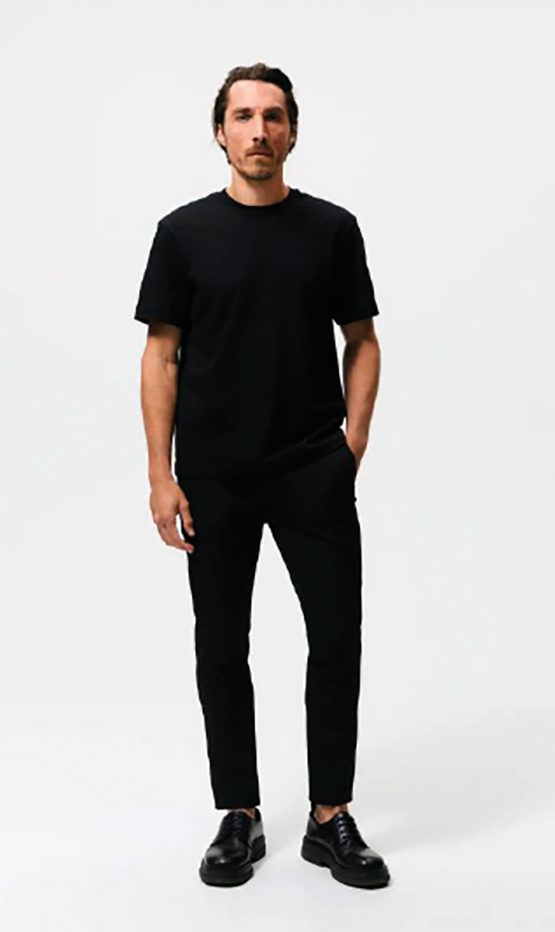 Modelo de cuerpo entero con camiseta y pantalón negros sobre fondo blanco