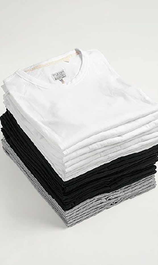Pila de camisetas dobladas en blanco, negro y gris